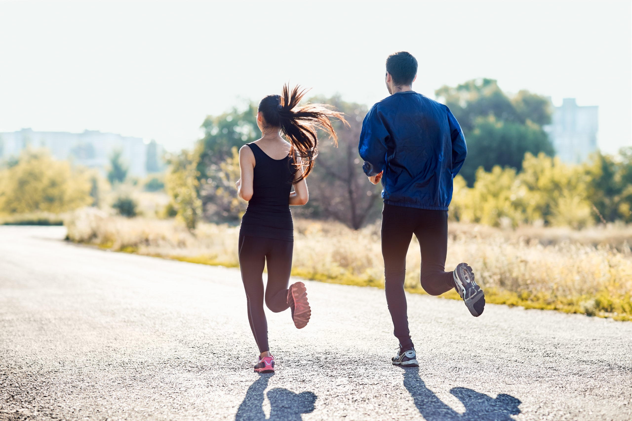 active sporty woman and man jogging on sunny day