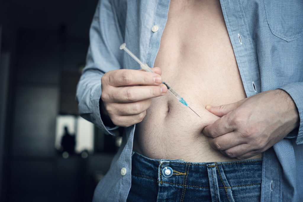 injecting insulin at home. young man hand using insulin syringe close up . self medication