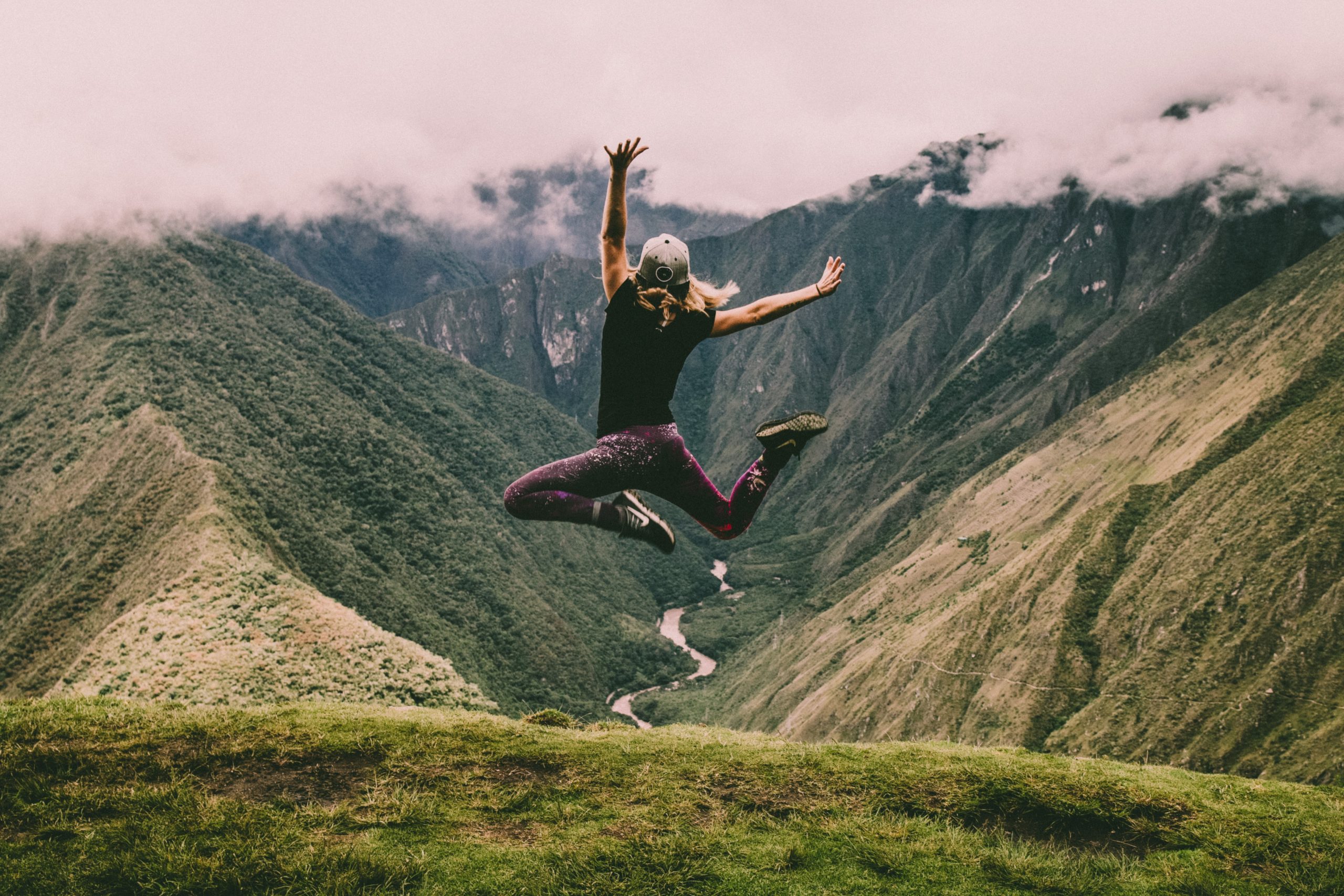 A woman joyfully jumping on a mountain